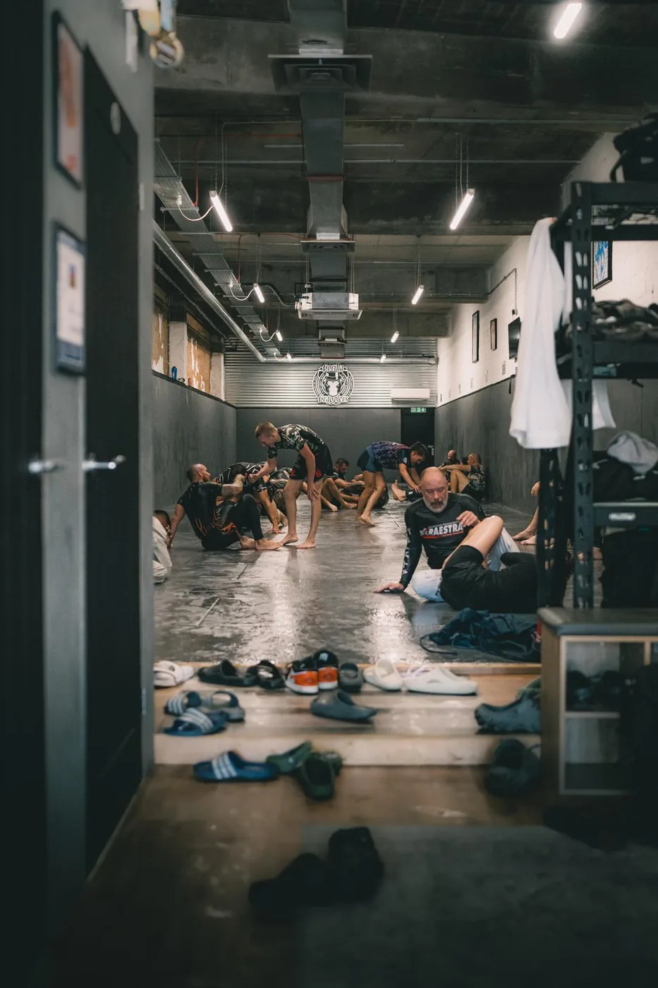 Adults training at Gorilla Grapplers, with mats, kit bags and rows of sliders by the door