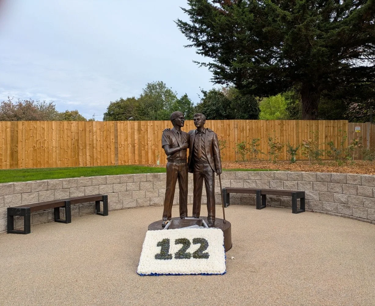 The Treloar's memorial garden at the entrance to the school in Holybourne, with a floral tribute reading 122 in front of the bronze statue.